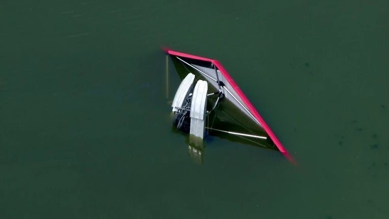 The hang glider aircraft is seen half submerged in the waters of Clear Lake
