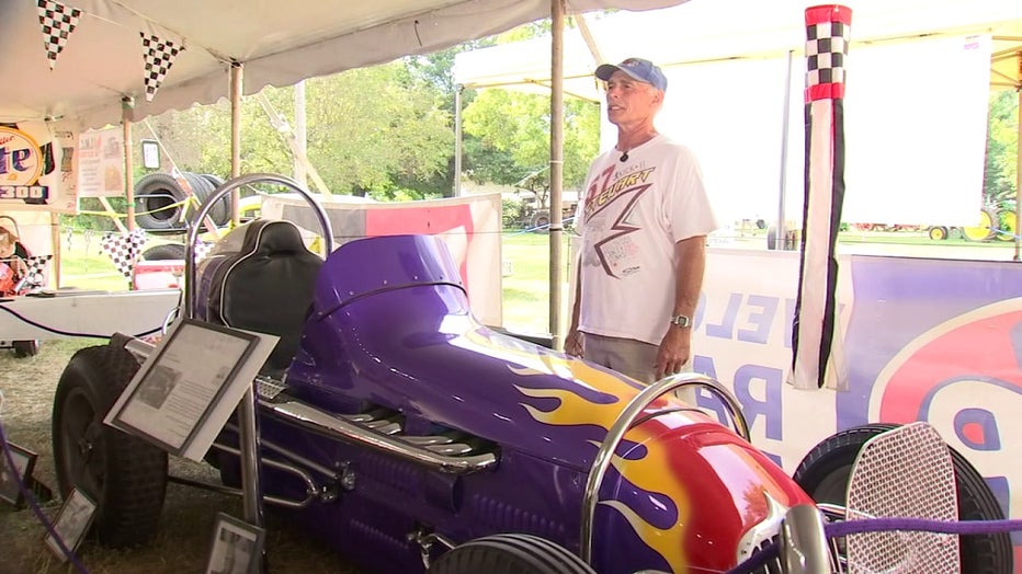 Man stands next to restored stock car