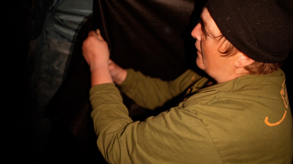 John Reps uses a paperclip to cover an opening in a tent a the Quarry encampment in Minneapolis. (FOX 9)