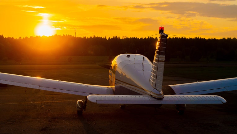 Rear view of a parked small plane on a sunset background. A silhouette of a grounded private jet at dusk. Piper Cherokee individual propeller aircraft