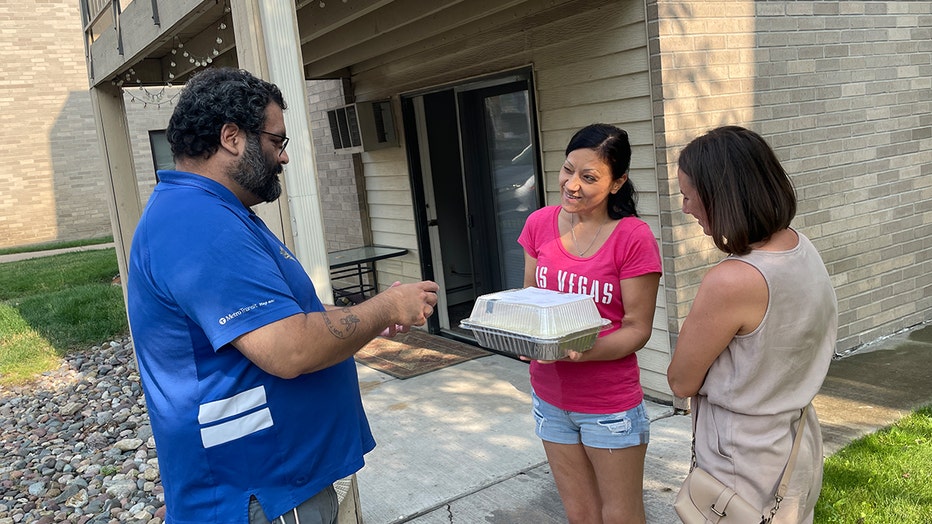 Anthony de Sam Lazaro of the Wonderwall, hands a dish to Olha, a Ukrainian refugee settling in Minnesota. (FOX 9)