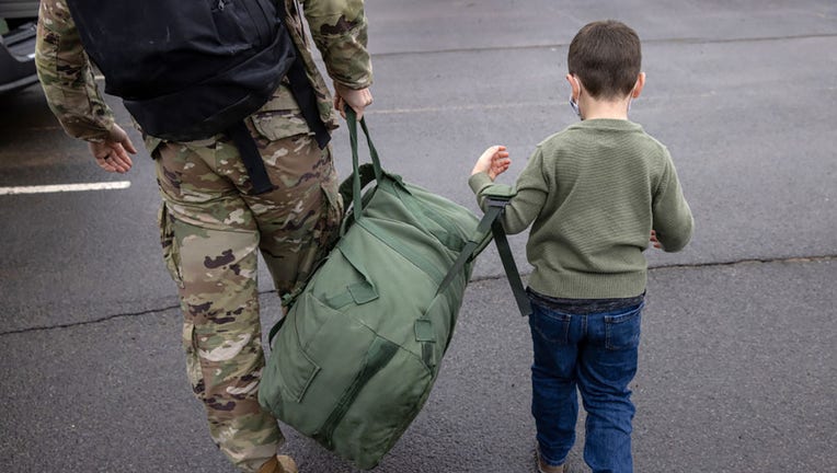 FILE - A 5-year-old helps his father in the U.S. Army carry a duffel after soldiers returned home from a 9-month deployment to Afghanistan in a file image dated Dec. 10, 2020, at Fort Drum, New York. (Photo by John Moore/Getty Images)