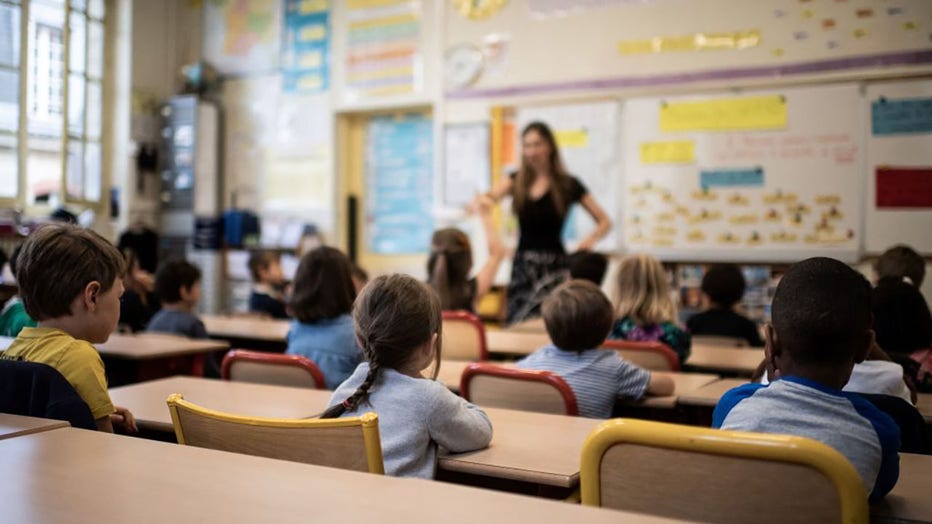 FILE - Children listen to their teacher as they sit in a classroom on the first day of the start of the school year on Sept. 2, 2019. (Photo by MARTIN BUREAU/AFP via Getty Images)