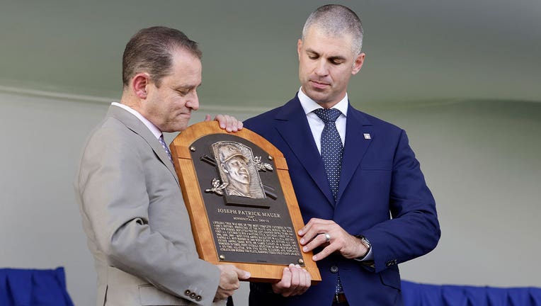 Joe Mauer accepts his Hall of Fame plaque from Hall of Fame President Josh Rawitch on stage in Cooperstown.