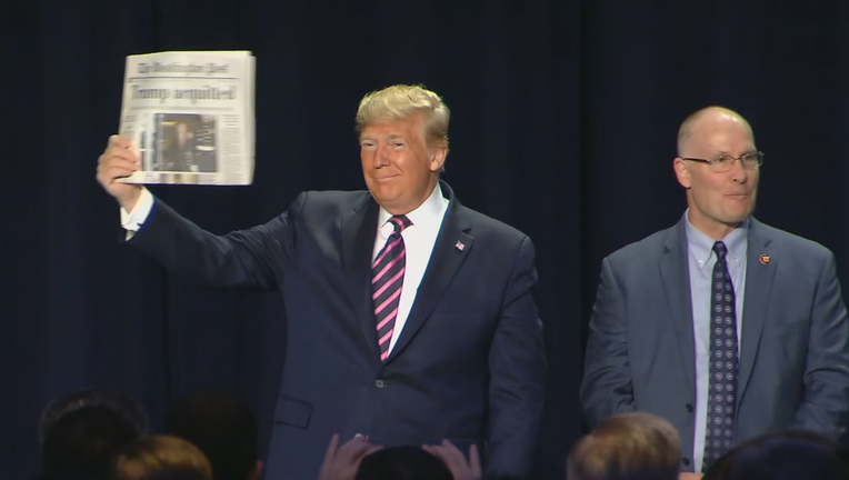 President Trump waves a newspaper with the headline, 