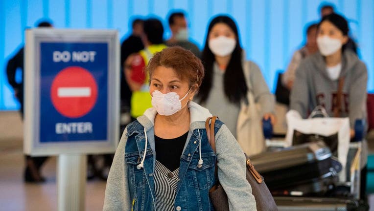 Passengers wear face masks to protect against the spread of the COVID-19, coronavirus, as they arrive at LAX airport in Los Angeles, California on Feb. 29, 2020.