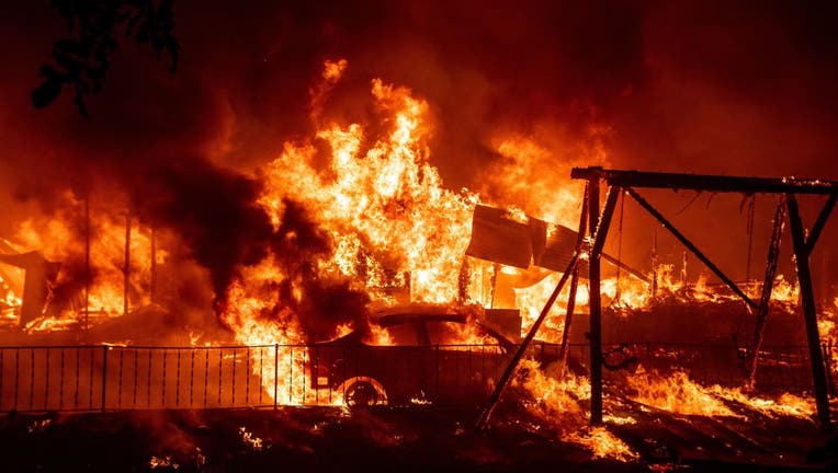 A home and car are completely engulfed in flames as the North Lightning Complex fire tears through Northern California