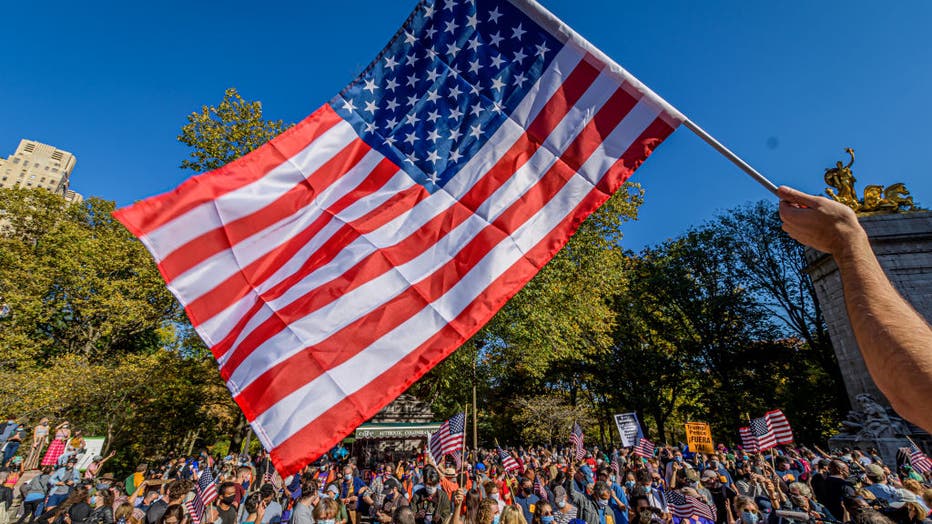 A participant holds a flag over the crowd of thousands celebrating the Biden-Harris projected victory on Nov. 7, 2020 in New York City (Photo by Erik McGregor/LightRocket via Getty Images)