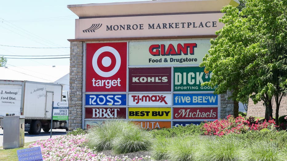 A sign at the entrance of Monroe Marketplace shows the logos