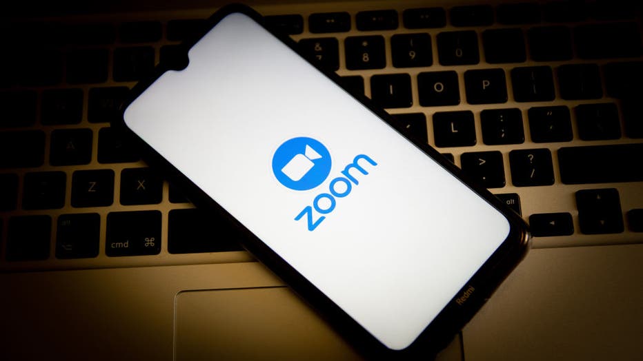 In this photo illustration, a Zoom logo seen displayed on a