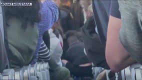 Flight attendants and passengers subdue unruly man who reportedly tried to open plane door, enter cockpit
