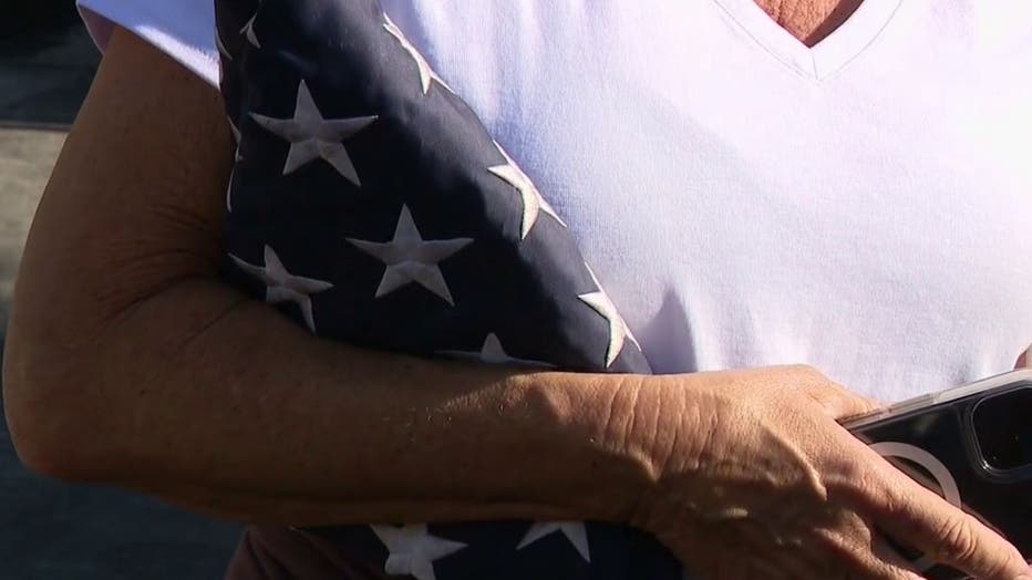 An Orange County mother clutches the U.S. flag that firefighters were able to salvage during the Coastal Fire.