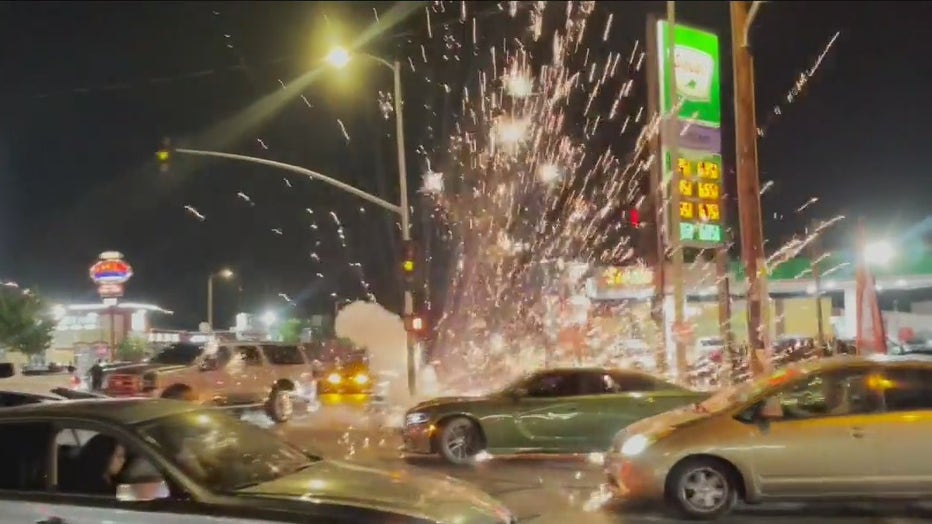 Image shows fireworks detonating near an intersection in South LA during a street takeover event. Cars are right near the fireworks blast.