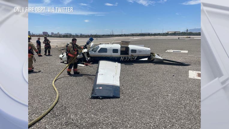 A small plane crashed on a runway. Firefighters stand next to plane with fire hose in hand.