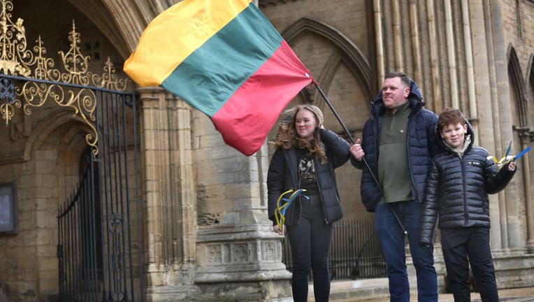 A father holding a Lithuanian flag arrives at the prayer
