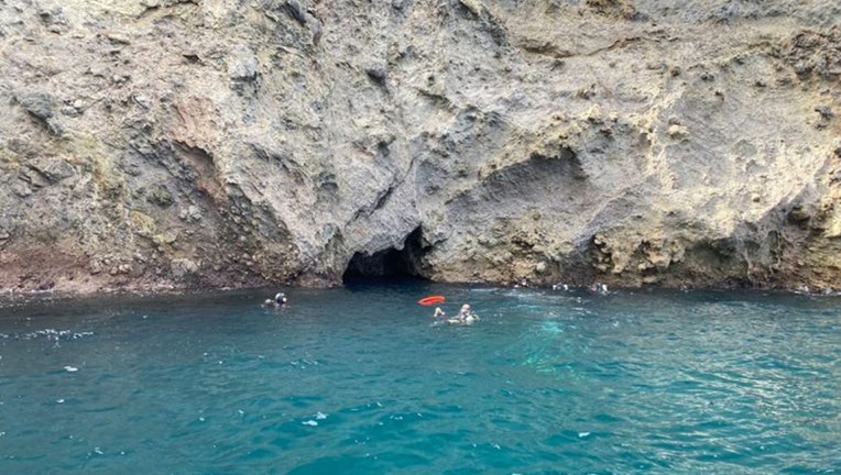 Divers in the water near a cave where a body was recovered near the ocean floor on Santa Cruz Island