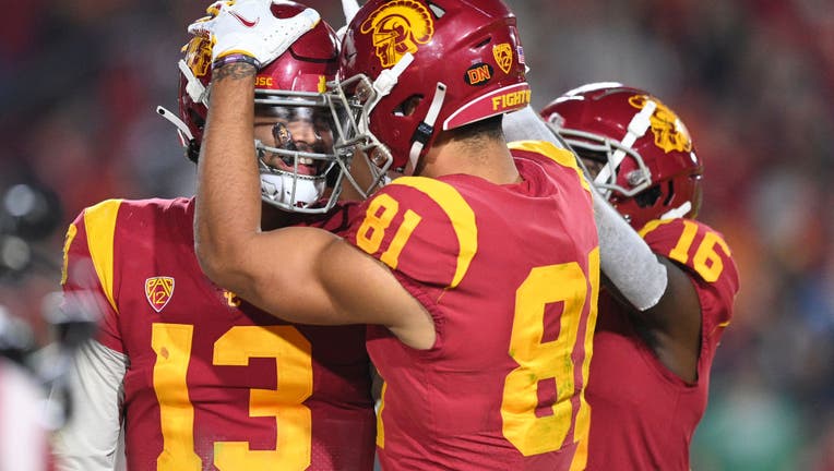 Caleb Williams of the USC Trojans with wide receivers Kyle Ford and Tahj Washington. Kyle Ford's hand on top of Williams' helmet