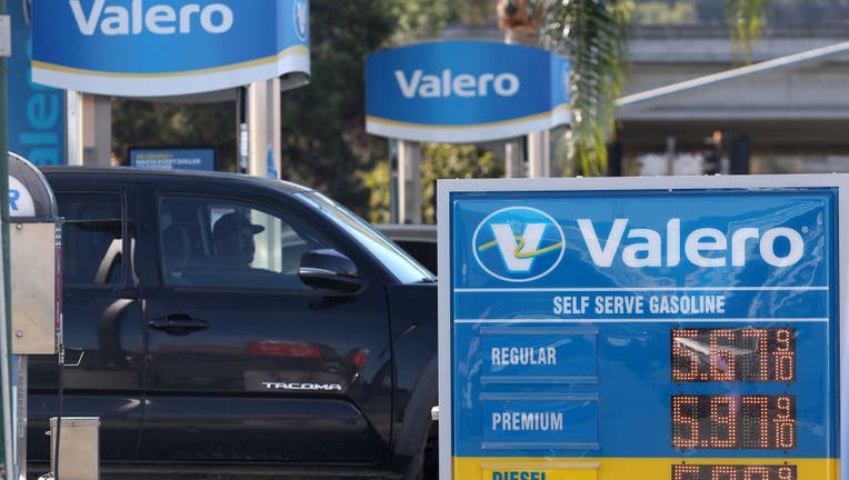 A Valero gas station sign in front of a black pickup truck