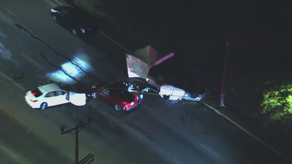Three cars involved in a crash. One white, one red, one silver, with the silver car upside down.