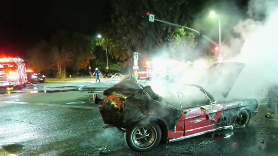 Firefighters extinguish a Mustang that caught fire after being rear-ended by another vehicle on West Mulholland Drive in Woodland Hills on Nov. 1, 2022.