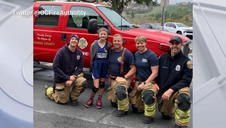 Firefighters kneeling with a young girl basketball player in front of a fire department pickup