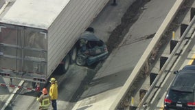 Vehicle collides into truck, getting stuck underneath