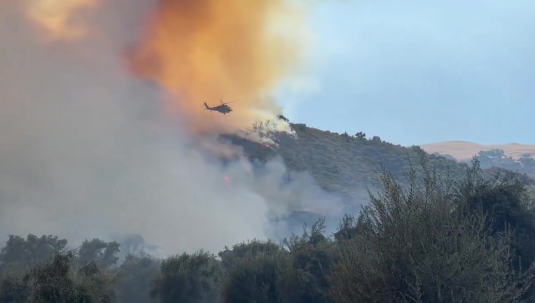 A helicopter over flames and smoke of the Felicia Fire near Lake Piru in Ventura County.