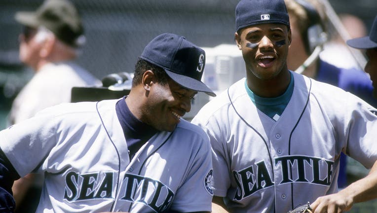 Outfielders Ken Griffey Jr. #24 (R) and coach Ken Griffey Sr. (L) of the Seattle Mariners laugh together circa 1993 before the start of a Major League Baseball game against the Oakland Athletics at the Oakland Coliseum in Oakland, California. Griffey Jr. played for the Mariners from 1989-99 and 2009-2010. (Photo by Focus on Sport/Getty Images)