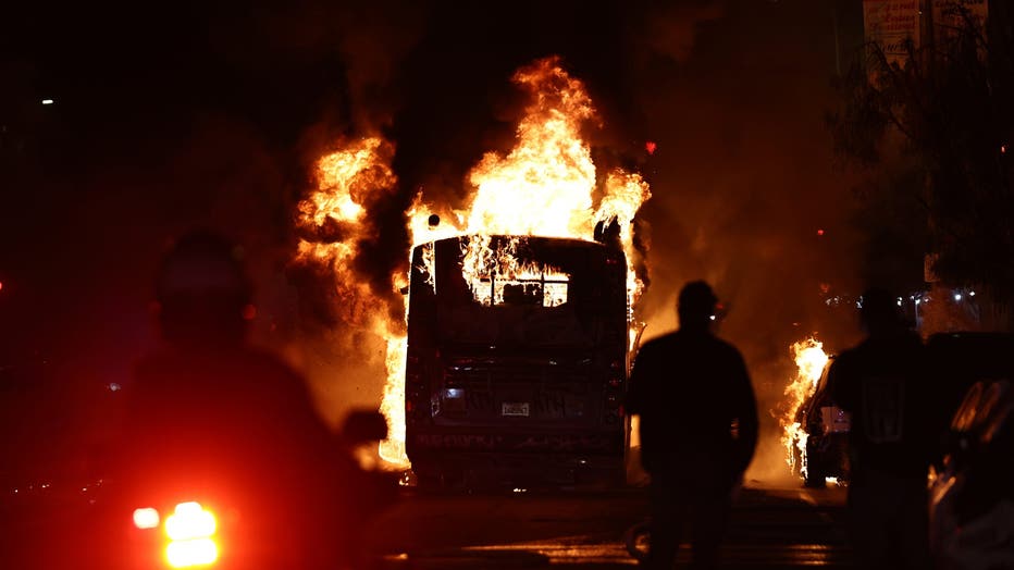 A Metro bus burns as police clear the area during unruly Dodger fan celebrations in Echo Park after the Los Angeles Dodgers defeated the New York Yankees in Game 5 to win the World Series on October 31, 2024 in Los Angeles, California. The Dodgers plan to hold a victory parade on Friday. (Photo by Mario Tama/Getty Images)