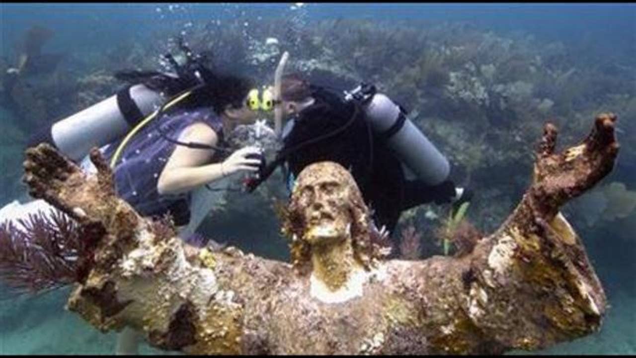 Couple wed beside 9foottall underwater Jesus statue