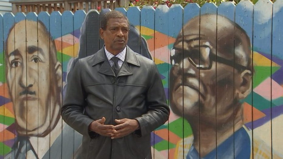 Ned Saturu stands in front of a mural.