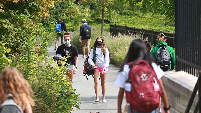 FILE - Students wearing masks walk around the Boston College Campus in Newton, MA on Sept. 14, 2020. There has been a coronavirus outbreak at the college.