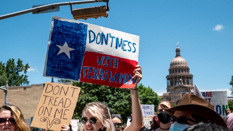 FILE: Protesters hold up signs as they march down Congress Ave at a protest outside the Texas state capitol on May 29, 2021, in Austin, Texas. (Photo by Sergio Flores/Getty Images)