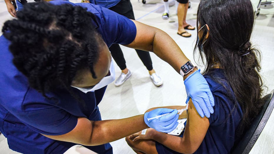 A nurse gives a girl a dose of the Pfizer vaccine at a COVID