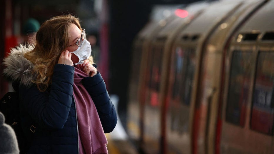A woman adjusts her face mask at Barons Court Underground station in London on November 29, 2021. - Britain will require all arriving passengers to isolate until they can show a negative PCR test against Covid-19 and is restoring a mandate to wear face masks in shops and public transport as part of its response to the new Omicron strain of Covid-19. (Photo by ADRIAN DENNIS / AFP) (Photo by ADRIAN DENNIS/AFP via Getty Images)