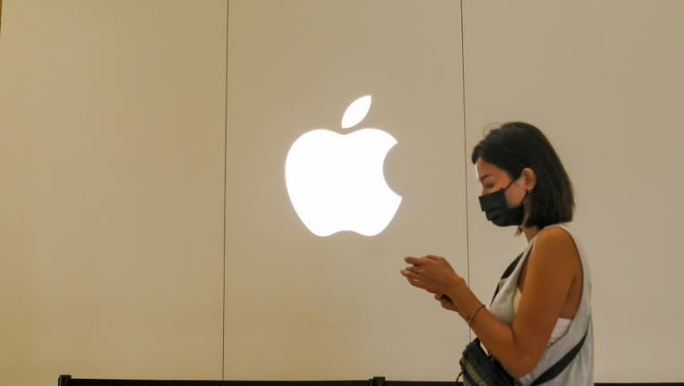 A woman walks past an Apple logo on the building of the A13
