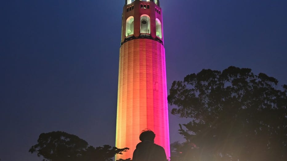 This is an image of Coit Tower with colorful lasers shooting out of the top.
