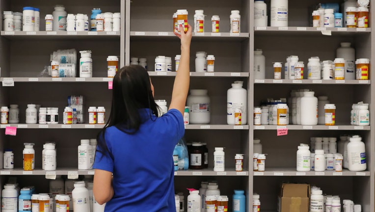 FILE IMAGE - A pharmacy technician grabs a bottle of drugs off a shelve at a pharmacy on Sept. 10, 2018, in Midvale, Utah. (Photo by George Frey/Getty Images)