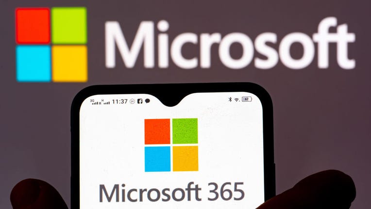 In this photo illustration, the Microsoft 365 logo is seen displayed on a smartphone and Microsoft logo in the background. (Photo Illustration by Igor Golovniov/SOPA Images/LightRocket via Getty Images)