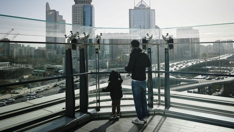 A man and a child look out at the Central Business District (CBD) in Beijing on Jan. 17, 2023. (Photo by WANG ZHAO/AFP via Getty Images)