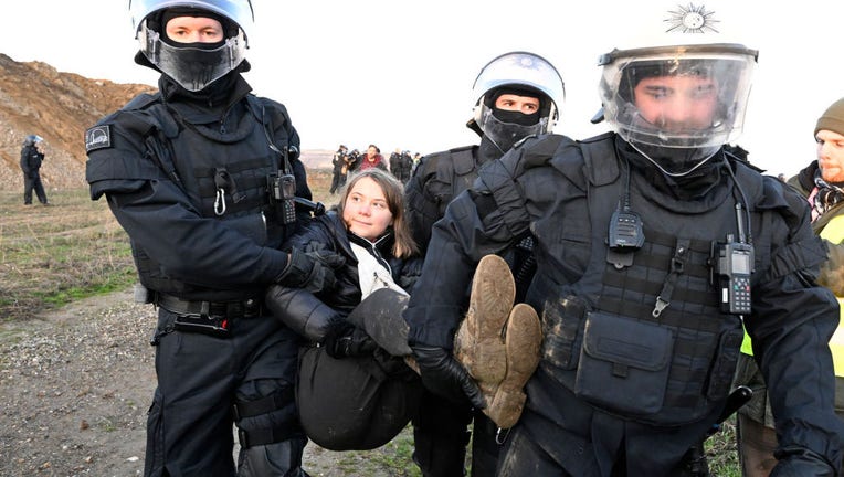 Police officers carry Swedish climate activist Greta Thunberg (M) out of a group of protesters and activists and away from the edge of the Garzweiler II opencast lignite mine on Jan. 17, 2023. (Photo by Roberto Pfeil/picture alliance via Getty Images)