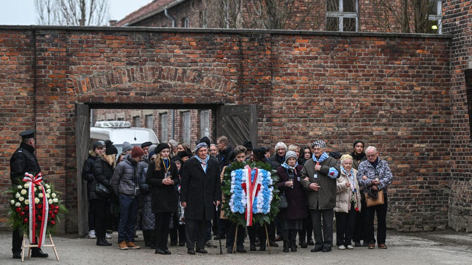 Survivors of the Auschwitz concentration camp and families arrive to lay wreaths honoring victims of the Nazi regime by the death wall during the Holocaust Remembrance day at the former Auschwitz I site on Jan. 27, 2023, in Oswiecim, Poland. (Photo by Omar Marques/Getty Images)