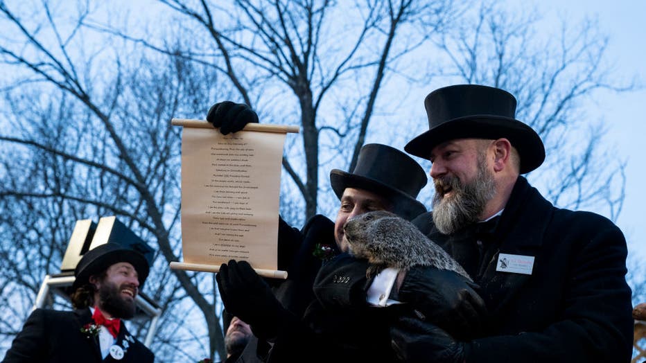 Vice President Dan McGinley shows a scroll to the crowd as Groundhog handler AJ Derume holds Punxsutawney Phil, who saw his shadow, predicting a late spring during the 136th annual Groundhog Day festivities on Feb. 2, 2023, in Punxsutawney, Pennsylvania. (Photo by Michael Swensen/Getty Images)
