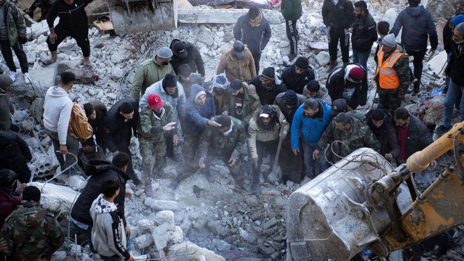 Residents search for victims and survivors amidst the rubble of a collapsed building in the regime-controlled town of Jableh in the province of Latakia, northwest of the capital Damscus, on Feb. 8, 2023, two days after a deadly earthquake in Turkey and Syria. (Photo by -/AFP via Getty Images)