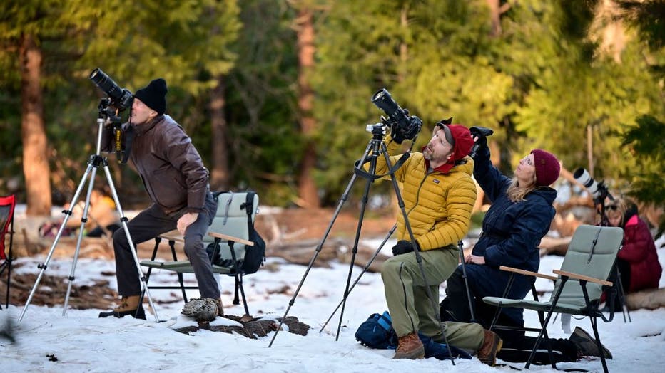 Photographers ready their tripods and cameras to capture the orange glow from water flowing off Horsetail Fall while backlit by the setting sun during the "Firefall" phenomenon in Yosemite National Park, California on Feb. 15, 2023. (Photo by FREDERIC J. BROWN/AFP via Getty Images)