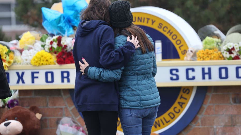 FILE - People embrace as they visit a makeshift memorial outside of Oxford High School on Dec. 1, 2021 in Oxford, Michigan. Four students were killed and seven injured when a gunman opened fire at the school. (Photo by Scott Olson/Getty Images)