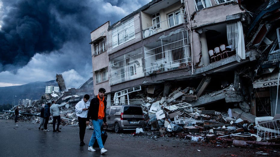 People walk past collapsed buildings on Feb. 7, 2023, in Iskenderun, Turkey. (Photo by Burak Kara/Getty Images)