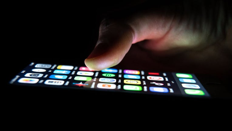 FILE - A person holds an iPhone in their hand with apps on it. (Photo by Silas Stein/picture alliance via Getty Images)