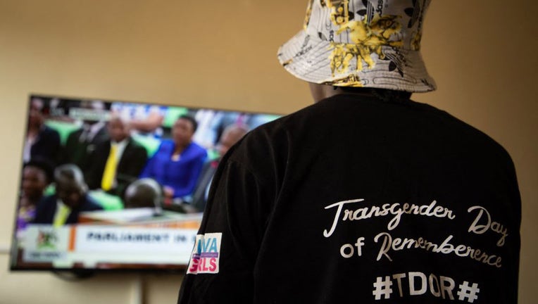 A Ugandan transgender woman who was recently attacked and currently being sheltered watches a TV screen showing the live broadcast of the session from the Parliament for the anti-gay bill, at a local charity supporting the LGBTQ Community near Kampala on March 21, 2023. (Photo by STUART TIBAWESWA/AFP via Getty Images)