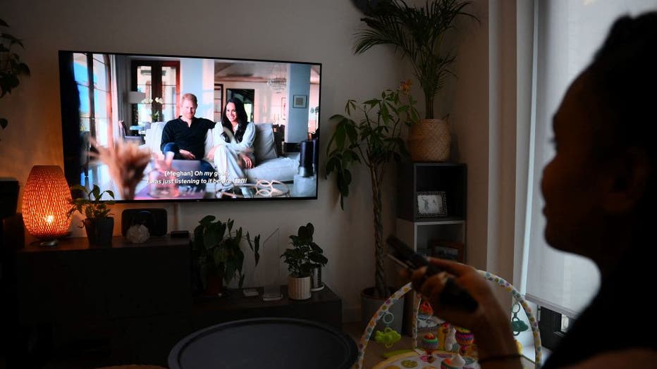 FILE - A woman poses as she watches an episode of the Netflix docuseries "Harry and Meghan" about Britain's Prince Harry, Duke of Sussex, and Britain's Meghan, Duchess of Sussex, in London on Dec. 8, 2022. (Photo by DANIEL LEAL/AFP via Getty Images)